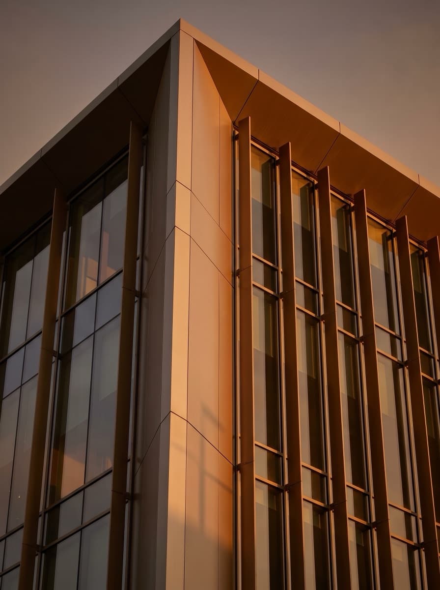 Cephe sistemleri — şampanya bronz alüminyum kompozit panel ve cam giydirme cephe, golden hour köşe detayı